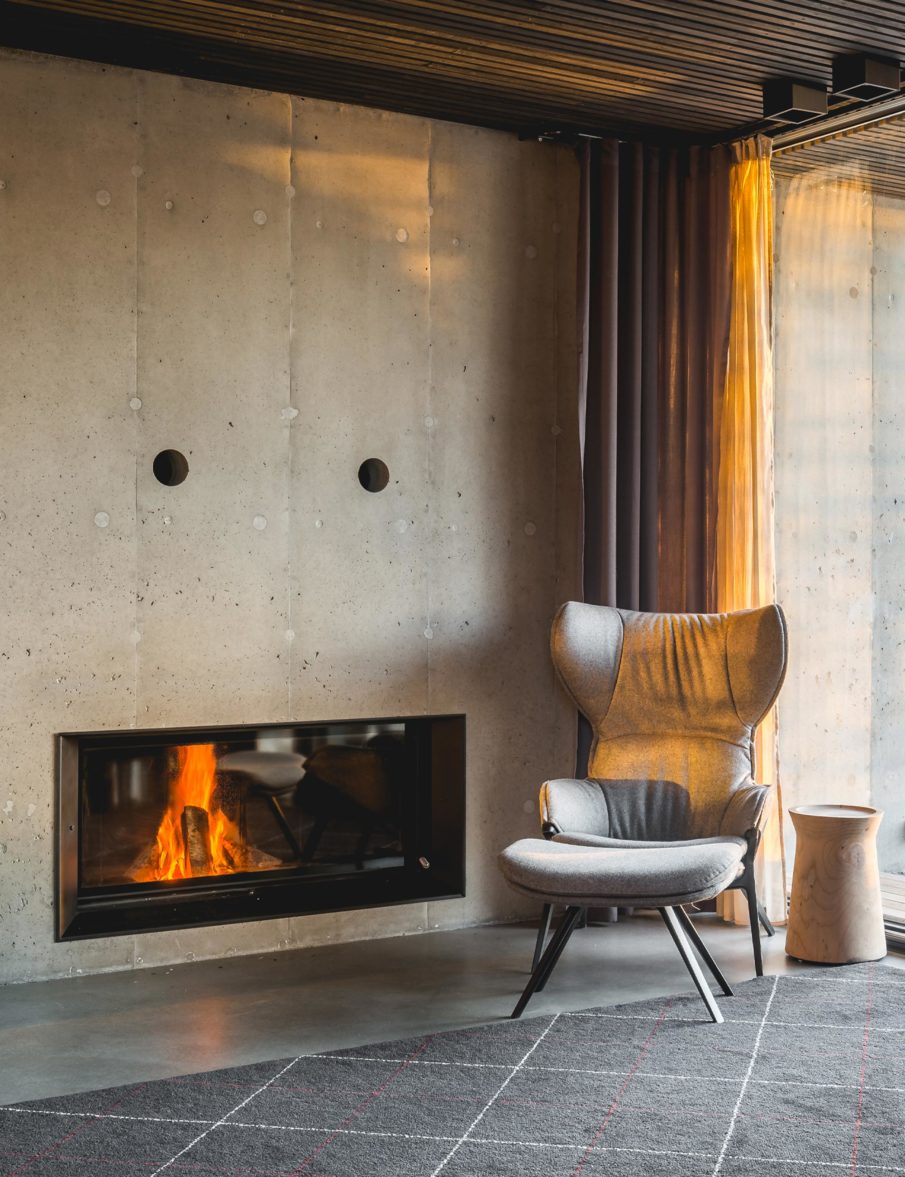 A snippet of a living room with an armchair in the corner in front of a fireplace.