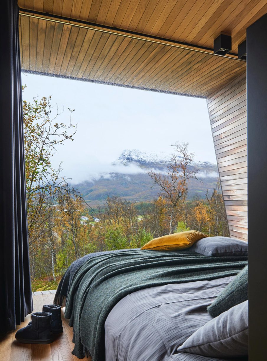 Bedroom with the bed facing a large window overlooking nature.