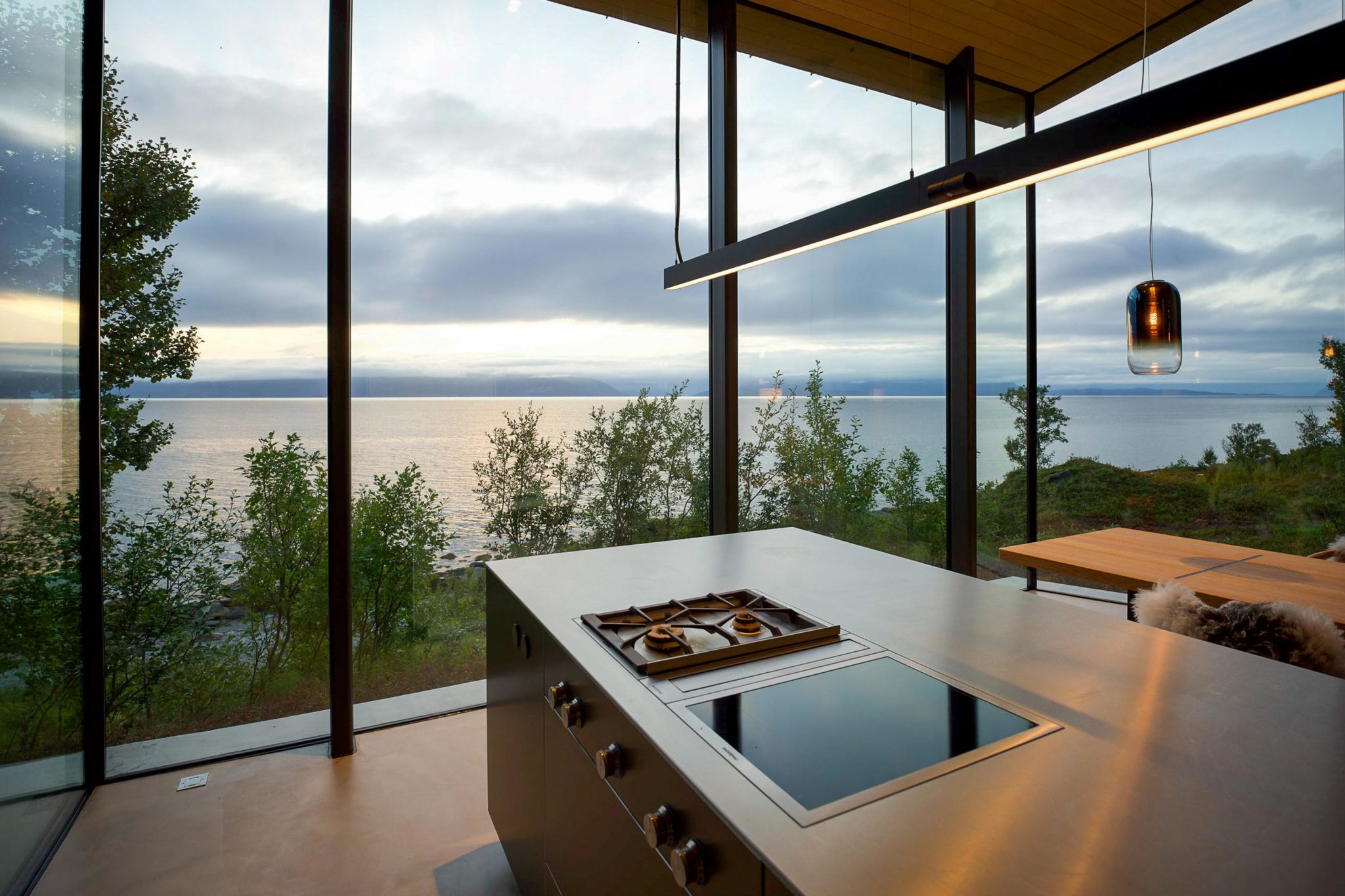 A part of a kitchen surrounded by large windows to bring nature inside.