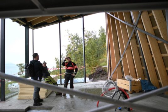 Three workers working on a cabin.