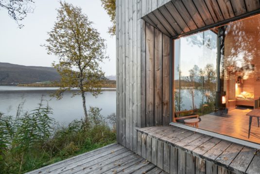 View from the terrace into a house. The house is situated in nature with a view over a lake.